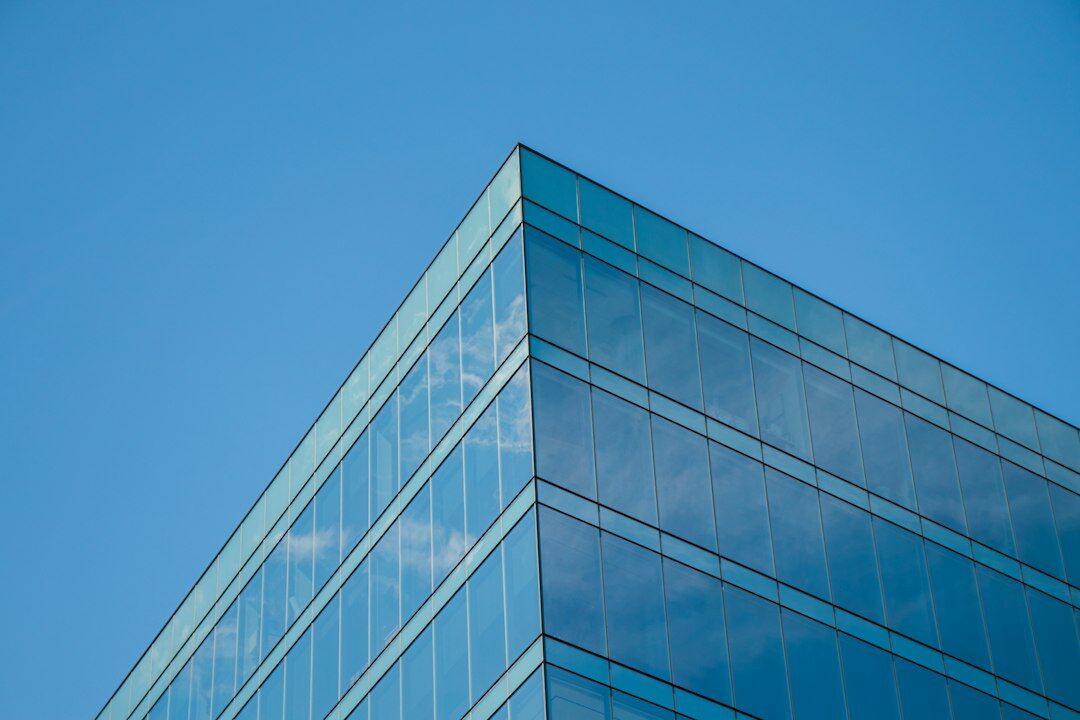 Modern glass office building exterior under a blue sky